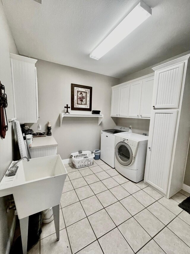 washroom featuring cabinet space, light tile patterned floors, separate washer and dryer, and a textured ceiling