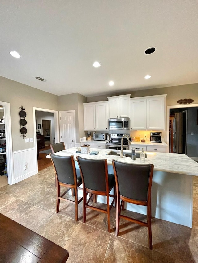 kitchen with stainless steel appliances, light countertops, visible vents, and white cabinetry