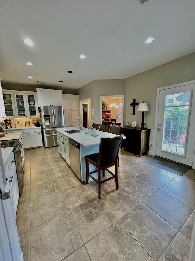 kitchen featuring white cabinets, an island with sink, glass insert cabinets, stainless steel appliances, and a sink