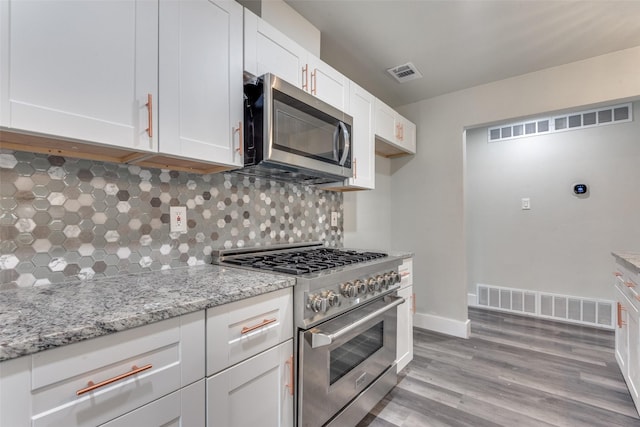 kitchen featuring stainless steel appliances, white cabinets, visible vents, and light stone countertops