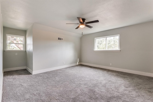 carpeted spare room featuring a healthy amount of sunlight, visible vents, and baseboards