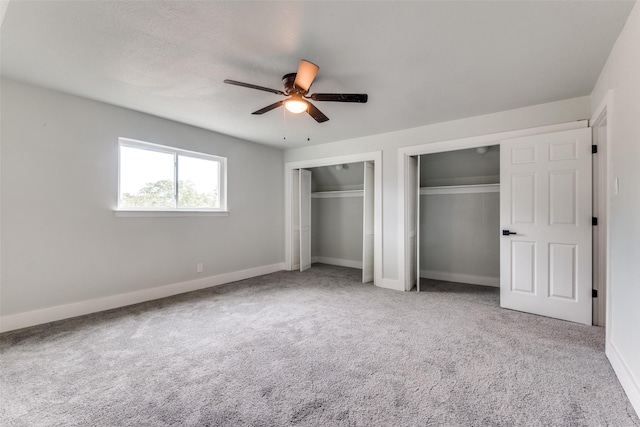 unfurnished bedroom with baseboards, carpet flooring, a ceiling fan, and multiple closets