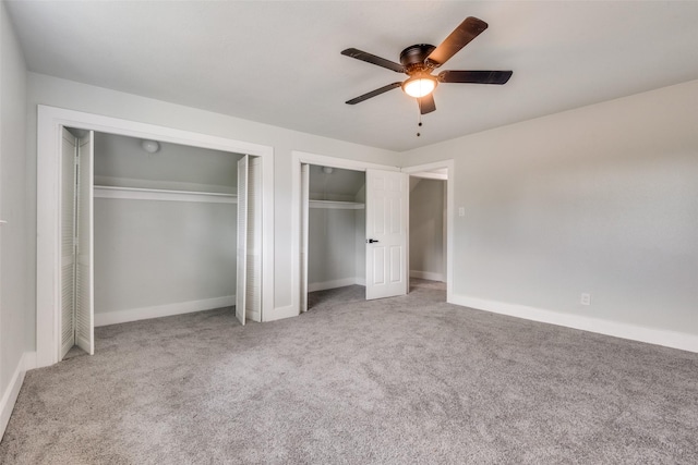 unfurnished bedroom with multiple closets, light carpet, and baseboards