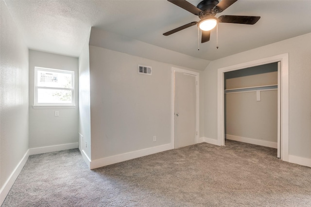 unfurnished bedroom featuring light carpet, baseboards, visible vents, a textured ceiling, and a closet