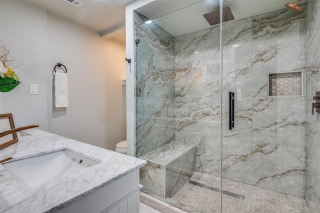 bathroom featuring toilet, visible vents, a marble finish shower, and vanity