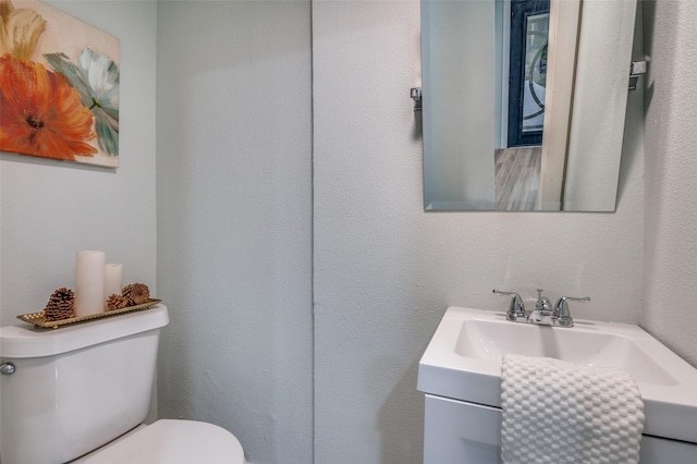 bathroom featuring a textured wall, vanity, and toilet