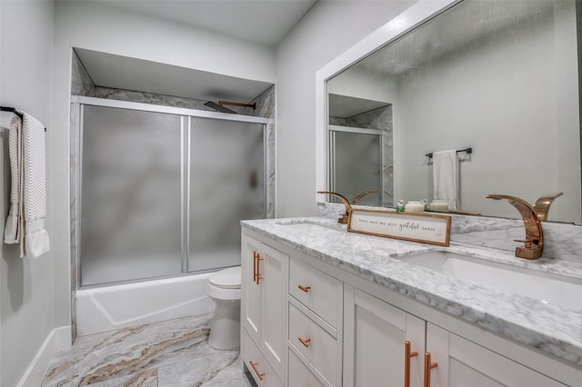 bathroom featuring combined bath / shower with glass door, a sink, toilet, and double vanity