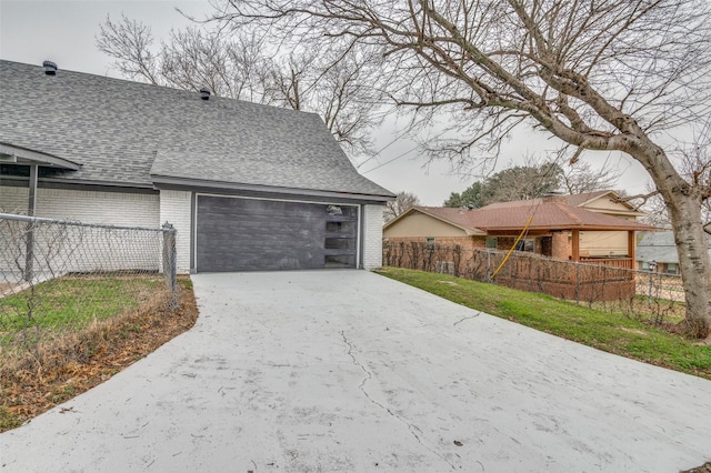 garage featuring fence and concrete driveway