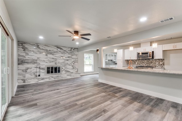 unfurnished living room with wood finished floors, visible vents, a sink, and a premium fireplace