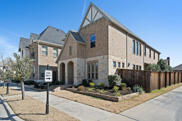 view of front of house featuring stone siding, brick siding, and fence