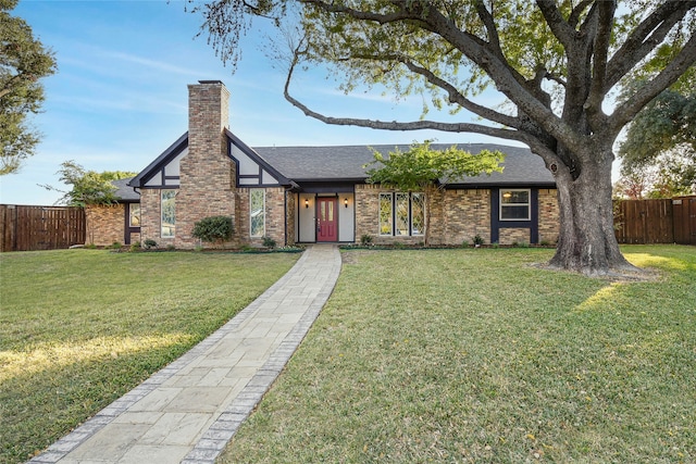 view of front of home featuring a shingled roof, fence, a chimney, and a front lawn