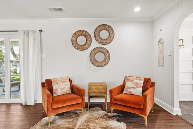 sitting room featuring ornamental molding, arched walkways, dark wood-type flooring, and visible vents