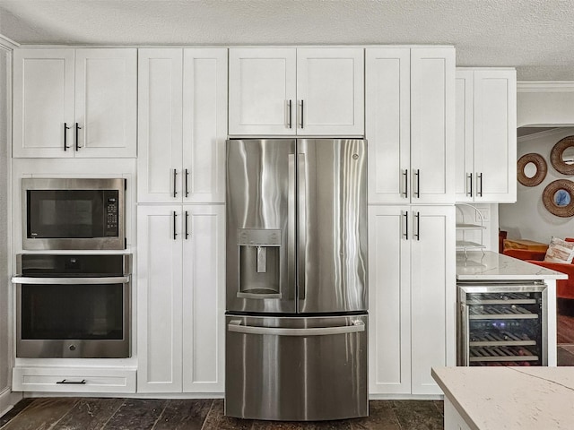 kitchen featuring wine cooler, appliances with stainless steel finishes, white cabinets, a textured ceiling, and light stone countertops