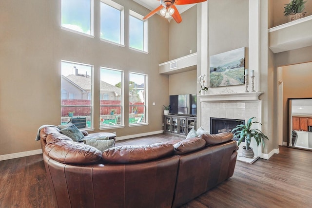 living room featuring dark wood-style flooring, a fireplace, and a wealth of natural light