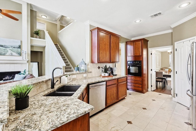 kitchen featuring light stone counters, a fireplace, visible vents, appliances with stainless steel finishes, and a sink