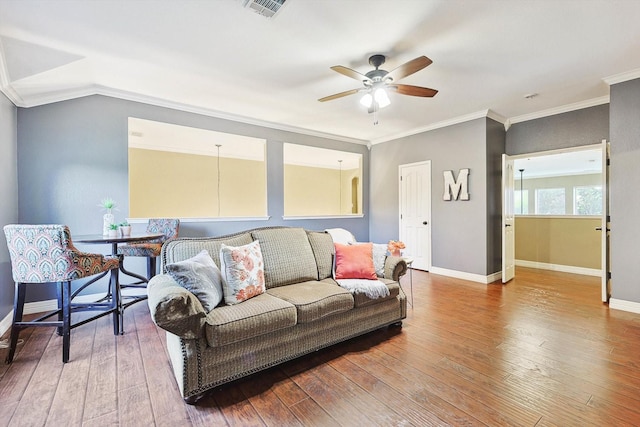 living room featuring baseboards, visible vents, wood finished floors, and ornamental molding