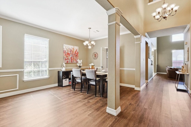 dining space with a chandelier, crown molding, ornate columns, and wood finished floors