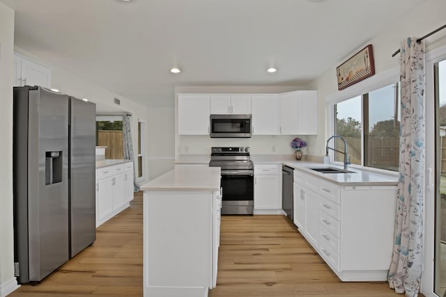 kitchen with stainless steel appliances, a center island, light countertops, and white cabinetry