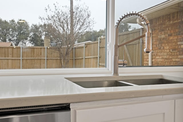 exterior space featuring brick wall, stainless steel dishwasher, and a sink