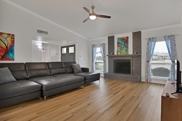 living area with light wood-style floors, a fireplace, vaulted ceiling, and ornamental molding