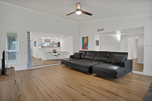 living area with baseboards, ornamental molding, visible vents, and light wood-style floors