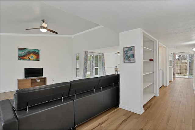 living room with light wood finished floors, ceiling fan, baseboards, and crown molding