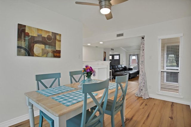 dining space featuring baseboards, visible vents, ceiling fan, and wood finished floors