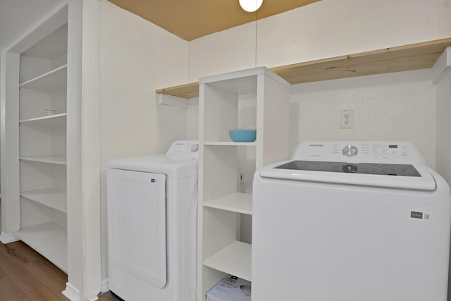 laundry area with laundry area, washing machine and dryer, and wood finished floors