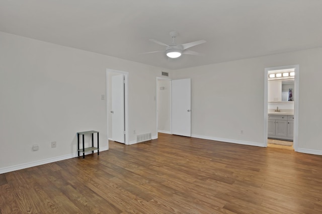 unfurnished room with ceiling fan, visible vents, baseboards, and wood finished floors