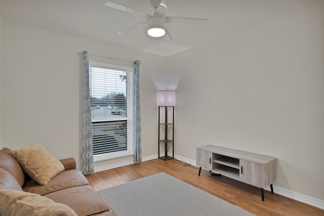 living area with light wood-style floors, ceiling fan, and baseboards