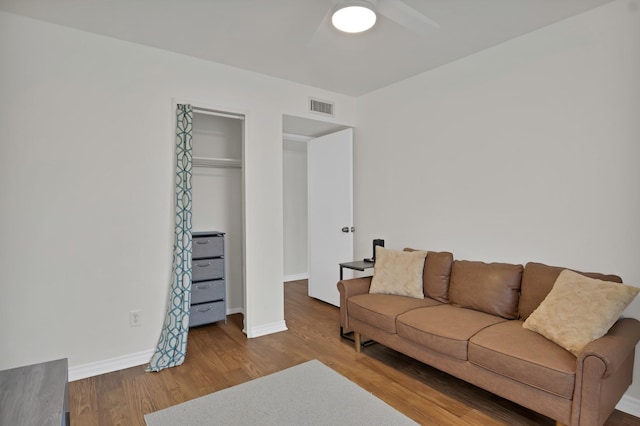 living area with visible vents, ceiling fan, baseboards, and wood finished floors