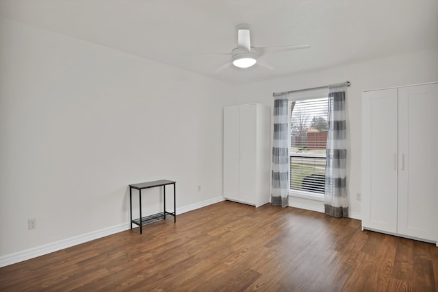 empty room featuring ceiling fan, baseboards, and wood finished floors