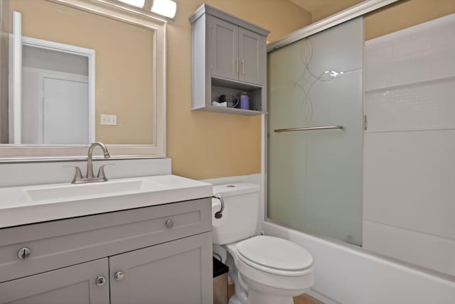 full bath with toilet, bath / shower combo with glass door, and vanity