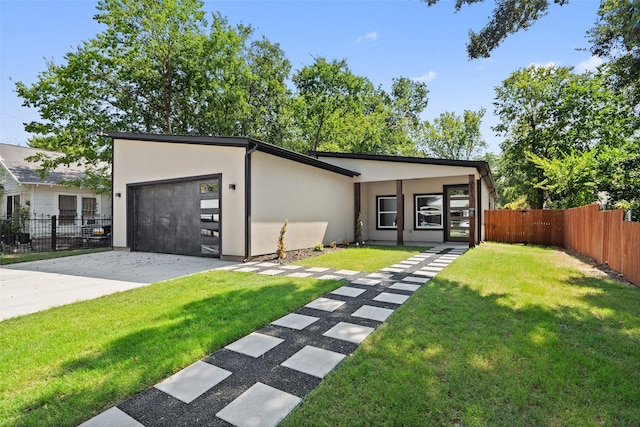 view of front of home with stucco siding, concrete driveway, an attached garage, a front yard, and fence