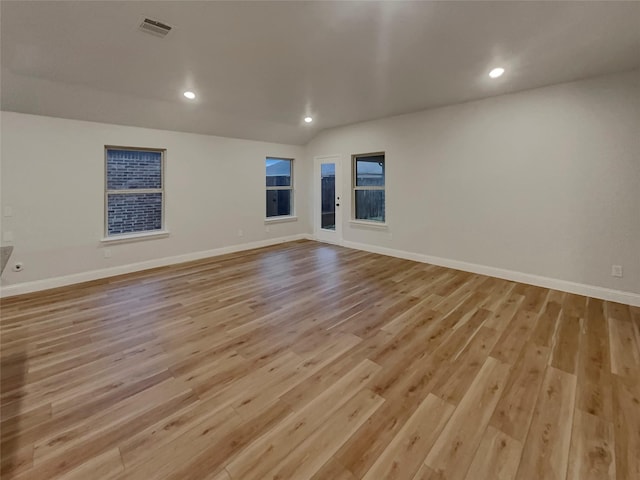 spare room with light wood-type flooring, visible vents, and baseboards