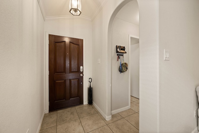 doorway to outside with arched walkways, light tile patterned flooring, baseboards, and crown molding