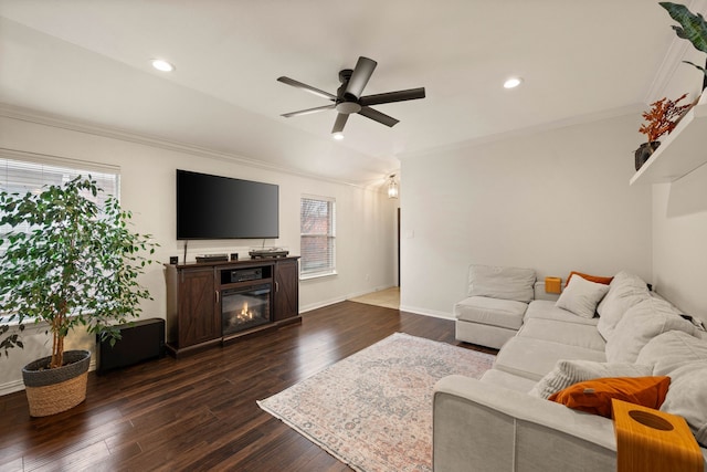 living room featuring baseboards, a ceiling fan, ornamental molding, dark wood-type flooring, and recessed lighting