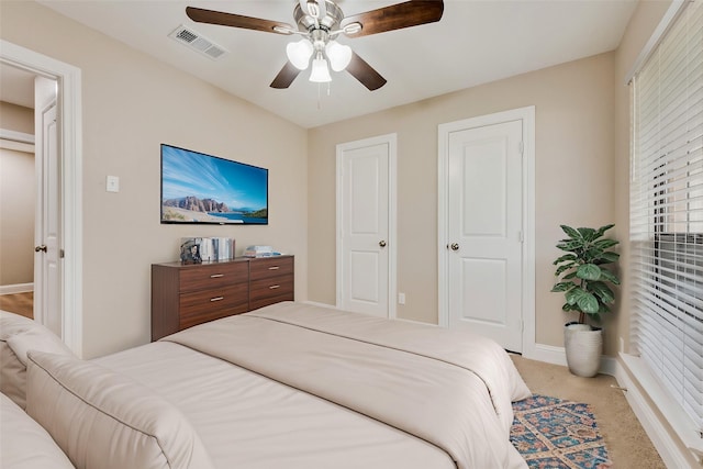 carpeted bedroom with a ceiling fan, visible vents, and baseboards