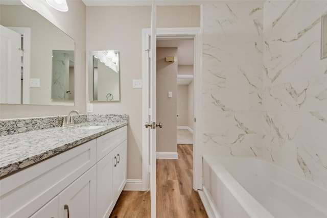 bathroom featuring shower / tub combination, wood finished floors, vanity, and baseboards