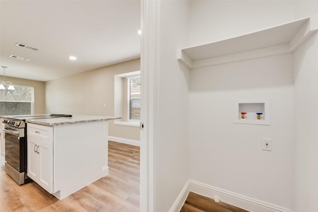 kitchen with visible vents, hanging light fixtures, white cabinets, light wood-type flooring, and stainless steel electric range