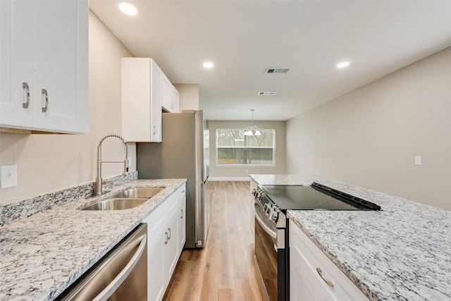 kitchen with visible vents, hanging light fixtures, stainless steel appliances, white cabinetry, and a sink