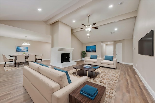 living area with a fireplace with raised hearth, light wood-style floors, beamed ceiling, baseboards, and ceiling fan with notable chandelier