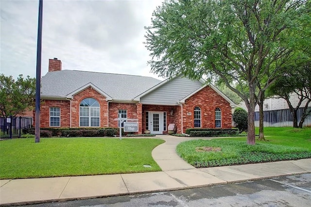 ranch-style house featuring brick siding, a front lawn, a chimney, and fence