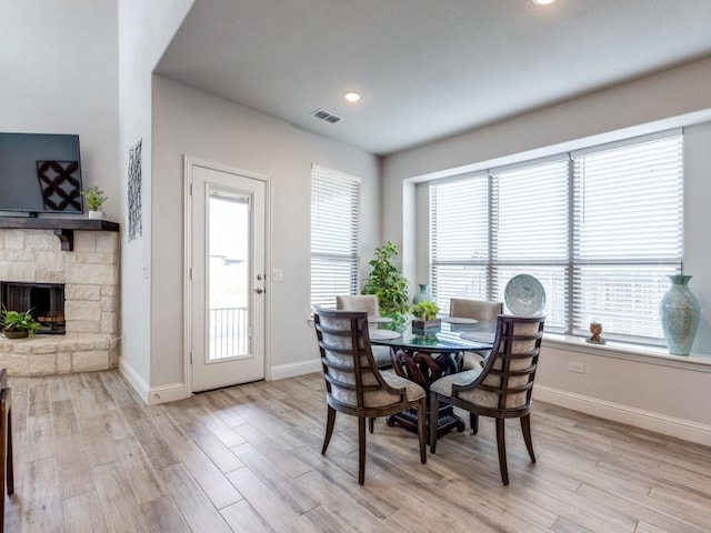 dining area with a fireplace, recessed lighting, visible vents, light wood-style flooring, and baseboards