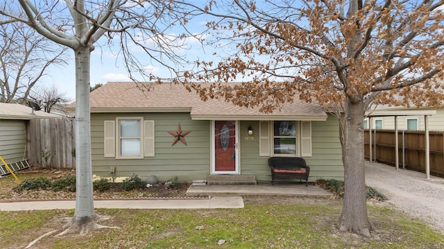 view of front of house with roof with shingles and fence