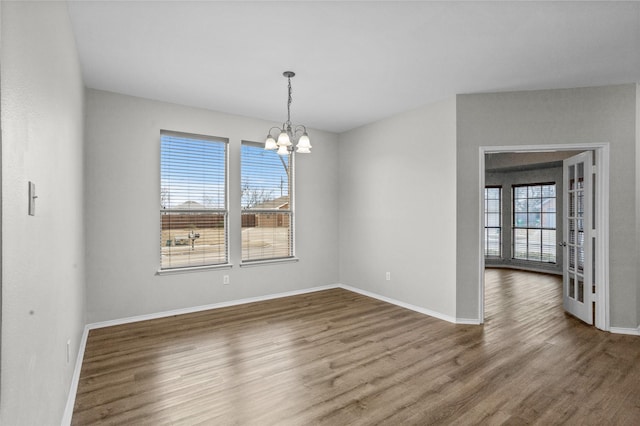 unfurnished dining area featuring baseboards, dark wood finished floors, and an inviting chandelier