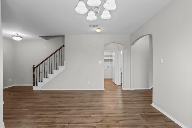 interior space with arched walkways, dark wood-style flooring, visible vents, and stairs