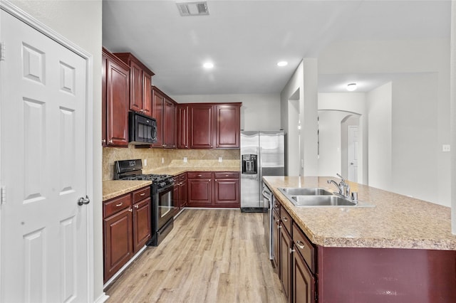 kitchen with visible vents, an island with sink, light countertops, black appliances, and a sink