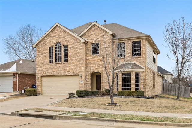 view of front facade with a garage, brick siding, driveway, and fence