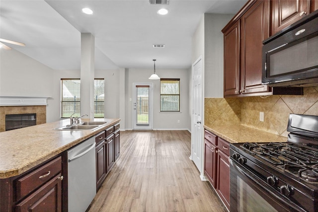 kitchen featuring decorative light fixtures, a sink, light countertops, black appliances, and backsplash